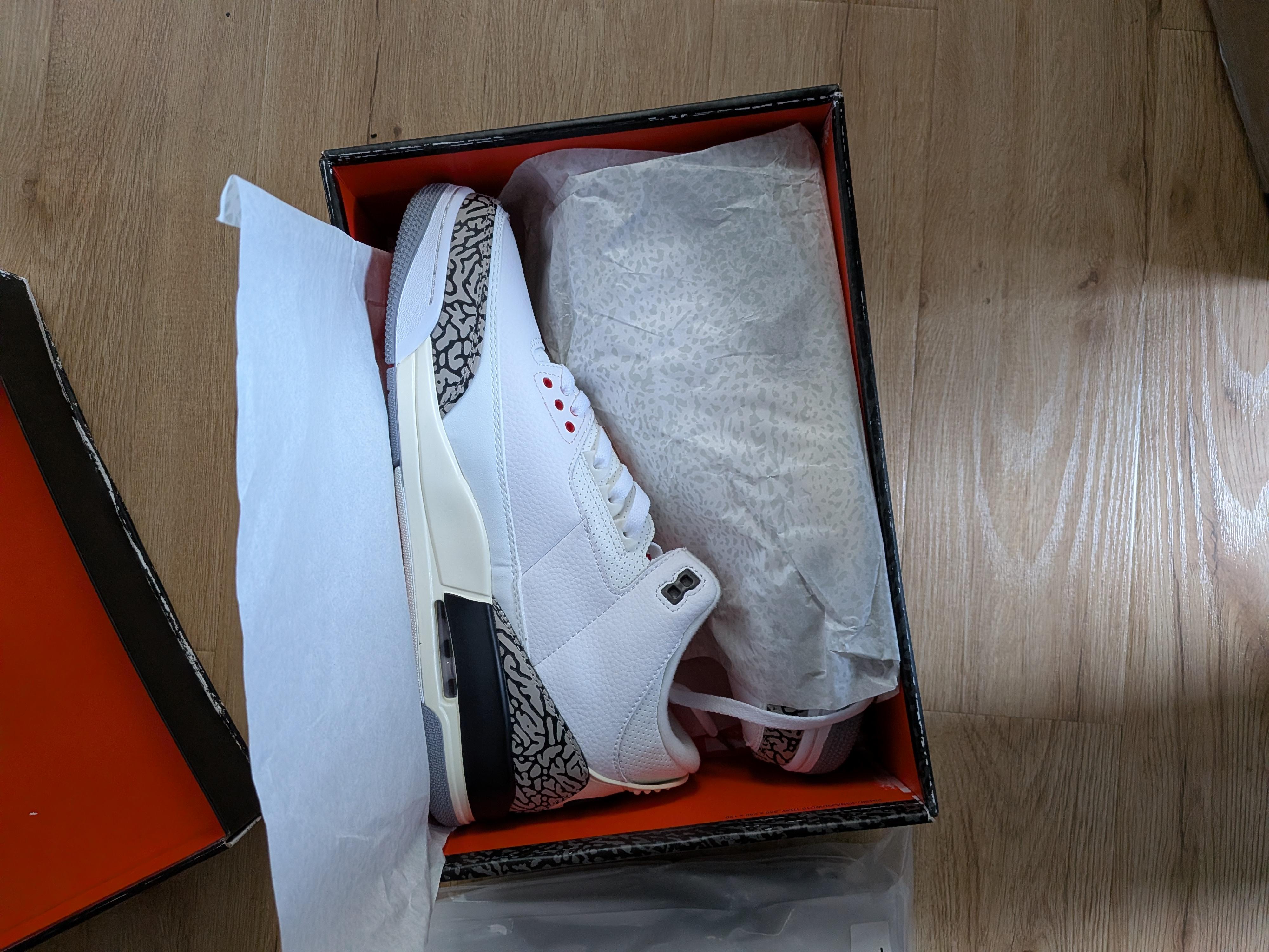 Two white sneakers with patterned toe and heel panels inside an open shoe box