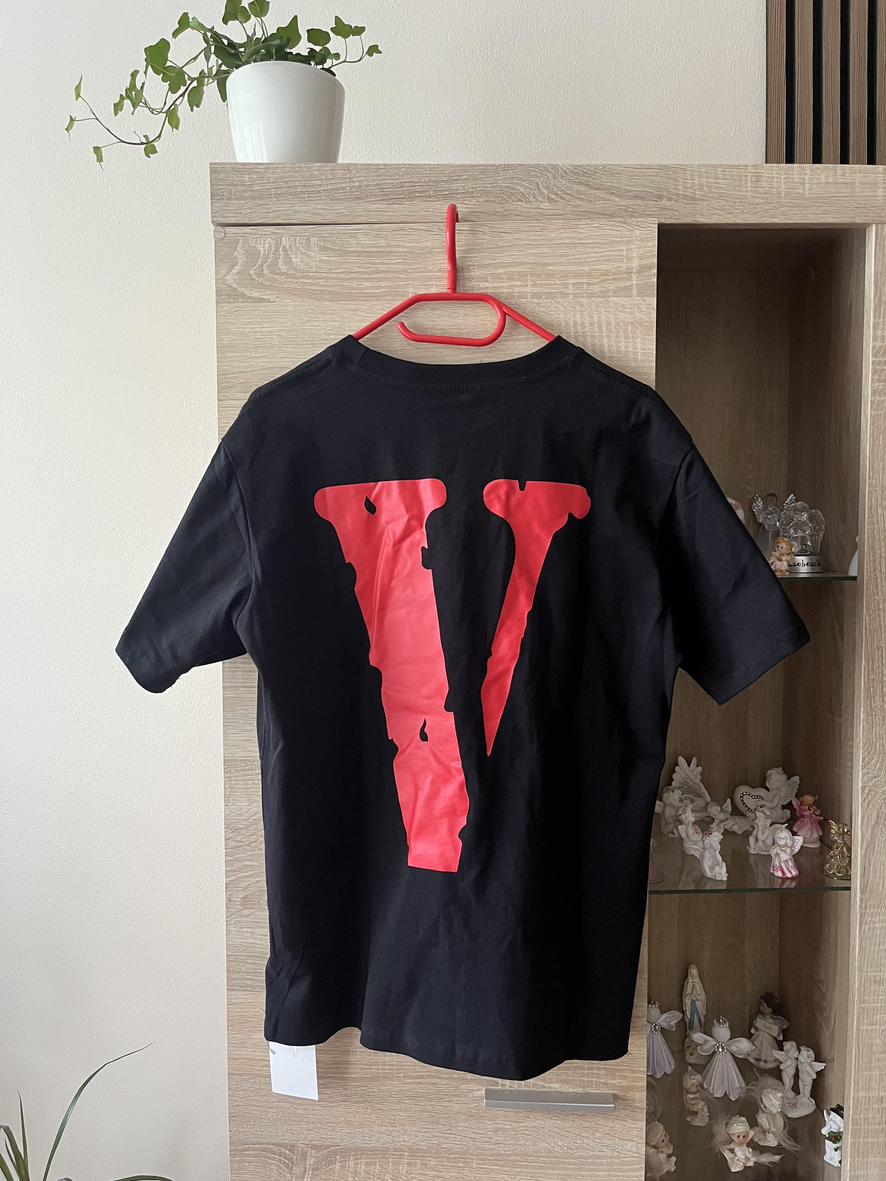 Black T-shirt on a red hanger with a large red V graphic on the back